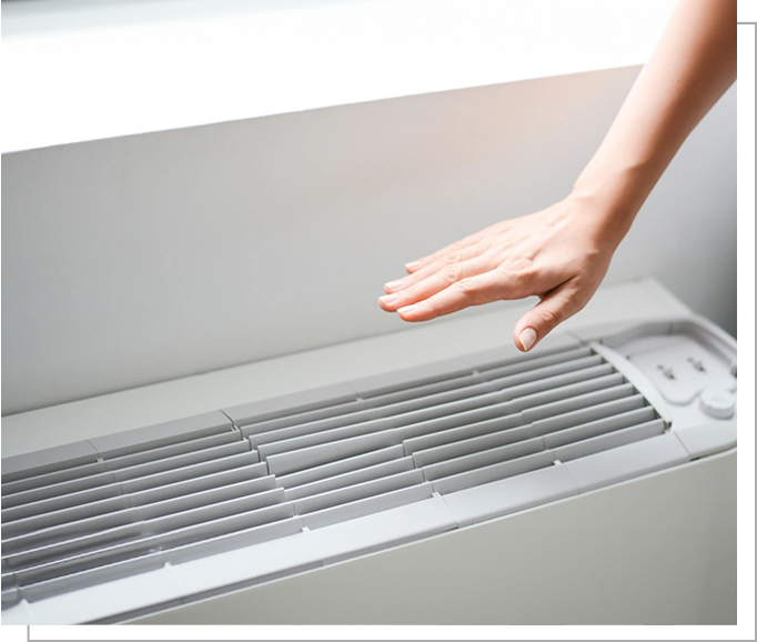 A person is touching the air vent of an electric heater.