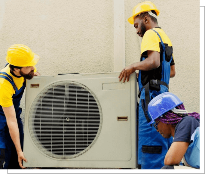 Three men working on a large air conditioner.