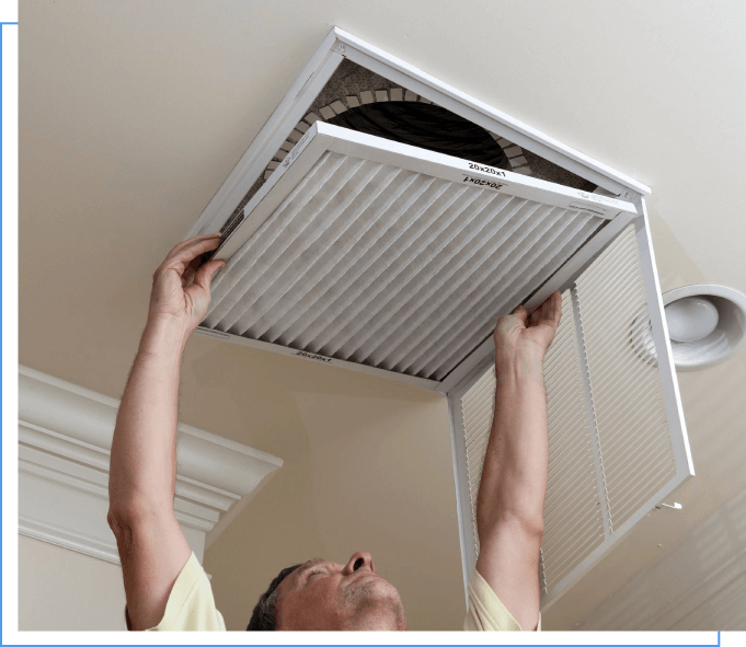 A man is holding an air filter up to the ceiling.