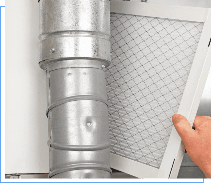 A person is holding an air filter in front of the wall.